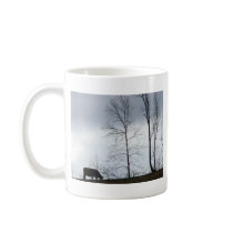 A Cow Eating Grass On The Hill With Naked Trees Coffee Mug