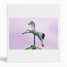 A white horse carousel statue against purple binder