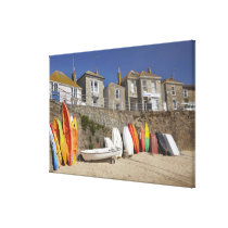 Kayaks and dinghies stacked against seawall at canvas print