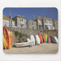 Kayaks and dinghies stacked against seawall at