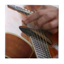 male hand holding pick on acoustic guitar ceramic tiles