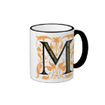 Or et tasse florale de "M" de noir -