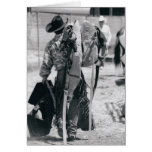Rear view of cowboy hauling gear greeting card