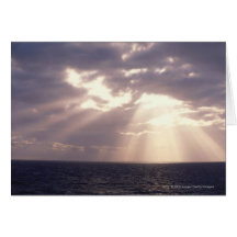 Setting sun shining through clouds over ocean greeting cards