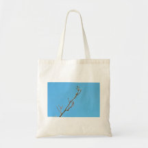 Snowy dry branch against bright blue background tote bag