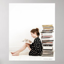 Teenage girl reading comic strip by pile of posters