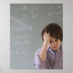 Teenaged boy in front of blackboard with math posters