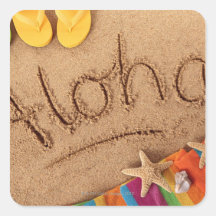 The word Aloha written on a sandy beach, with 2 Sticker