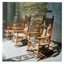 Three Wooden Rocking Chairs on Sunny Porch Tiles