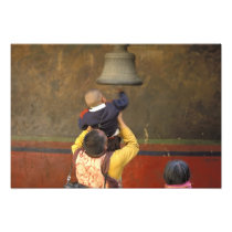 Tibetan Buddhist monk lifting a boy to ring a