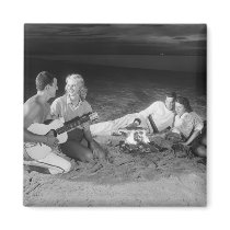 Two couples on beach sitting around campfire fridge magnets