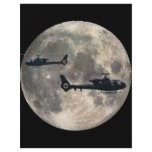 two helicopters silhouetted by a full moon