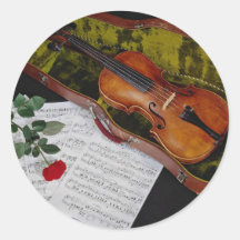 Violin and red rose on black background round sticker