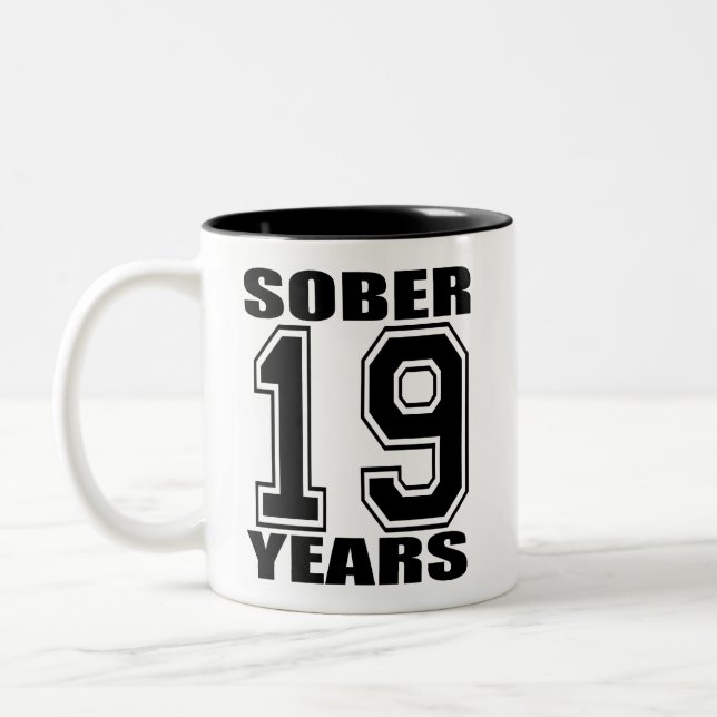 19 ans assagissent le noir sur la tasse blanche (Gauche)