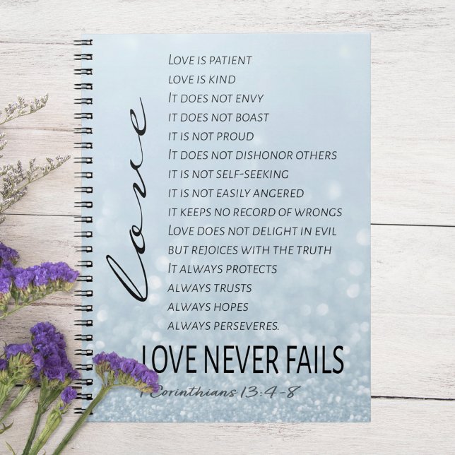 1 Corinthians 13 Love is Bible Verse Notebook (Corintians 13:4-8 Love Never Fails Notebook on White Table with Purple Flowers)