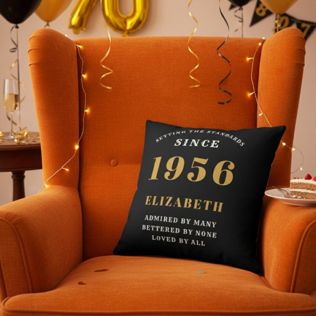 70th Birthday Gift Personalized 1956 Black Gold Throw Pillow (Personalized 70th birthday throw pillow on an orange velvet wingback chair)