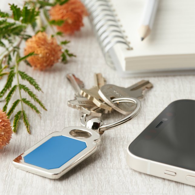 a blue background with a black and white clock keychain (Side)