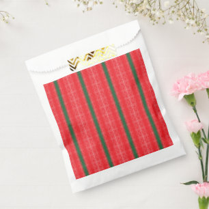 A bright red apple sits on a plain white surface. favour bag