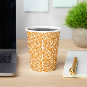 A brown and orange rug with a repeating pattern mo paper cups
