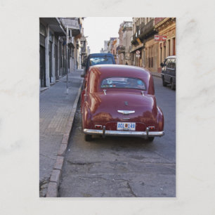 A classic old red Peugeot car parked on a street Postcard