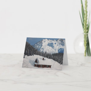 A cosy winter cottage, snowy mountains and forest holiday card