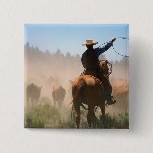 A cowboy out working the herd on a cattle 2 inch square button