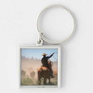 A cowboy out working the herd on a cattle keychain