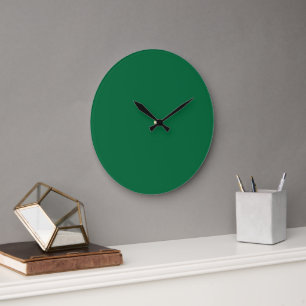 A deep green background contrasted by a crisp whit large clock