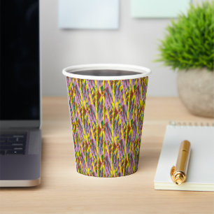A fluffy grey cat with green eyes sits on a window paper cups