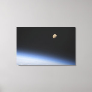 A gibbous moon visible above Earth's atmosphere 2 Canvas Print