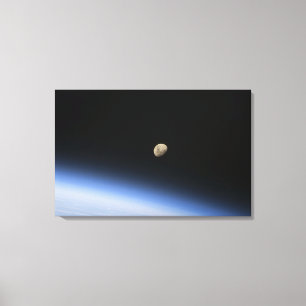 A gibbous moon visible above Earth's atmosphere Canvas Print