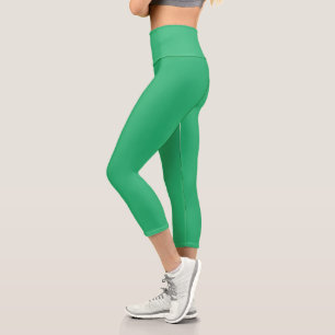 a green background with a white border capri leggings
