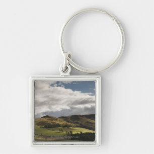 A Landscape With Rolling Hills And Clouds Overhead Keychain