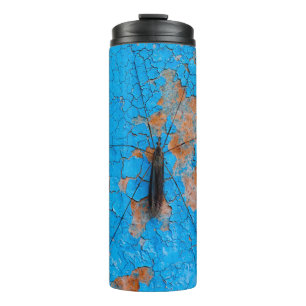 A large mosquito sits on an blue old cracked walla thermal tumbler
