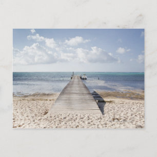 A long dock with a boat at the end stretches out postcard