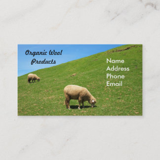 A lush green pasture with two sheep grazing business card