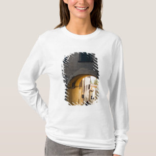 A person walking under an arch, down a hill in T-Shirt