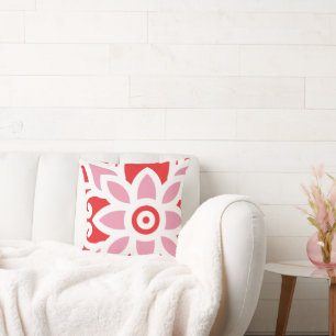 a red and white pattern with a flower on it throw pillow
