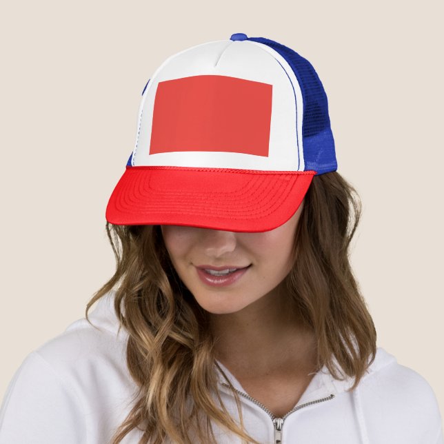 a red background with a white border trucker hat (In Situ)