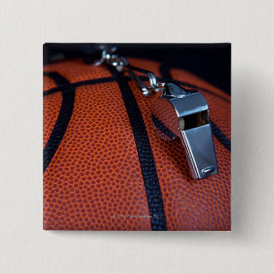 A referee's whistle rests on top of a 2 inch square button