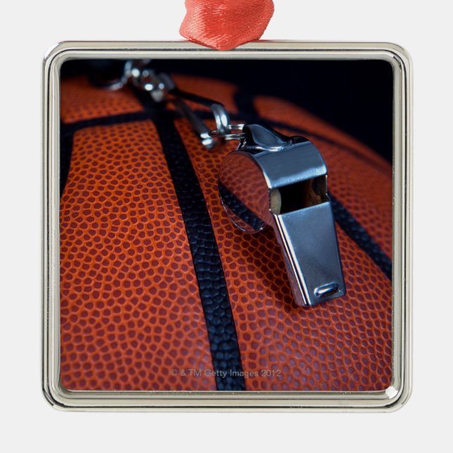 A referee's whistle rests on top of a metal ornament (Front)