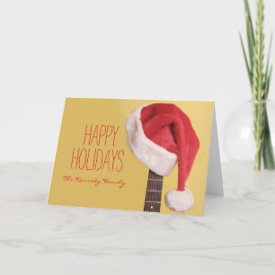 A Santa hat hangs on an acoustic guitar in front Holiday Card