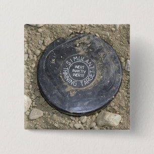 A simulated land mine 2 inch square button
