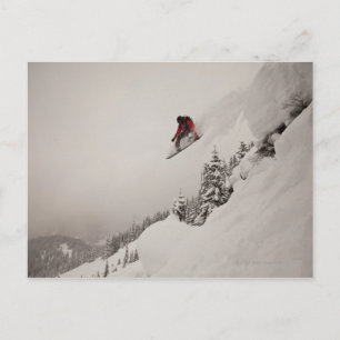 A snowboarder jumps off a cliff into powder in postcard