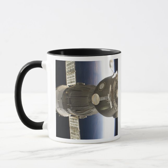 A Soyuz spacecraft backdropped by Earth Mug (Left)
