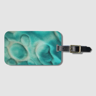 A swirling pattern in teal and light beige luggage tag