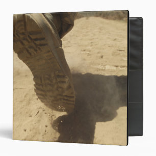 A US soldier walks along a dirt path Binder