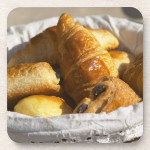 A wicker breakfast basket with croissants, and coaster