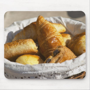 A wicker breakfast basket with croissants, and mouse pad