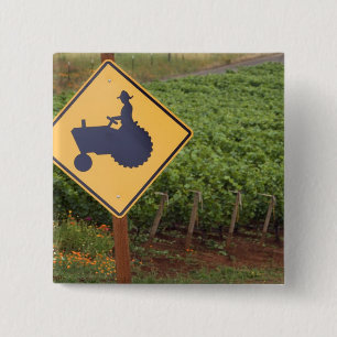 A yellow tractor crossing sign in the vineyard 2 inch square button